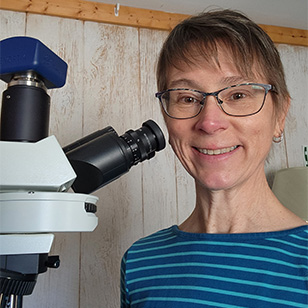A photo of Diane Winter, a staff scientists with a microscope.